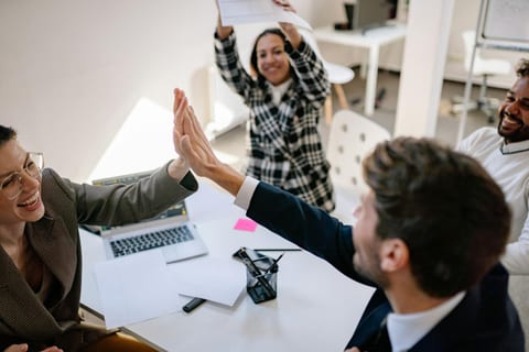 Kollegen geben sich lachend ein High-Five im Büro