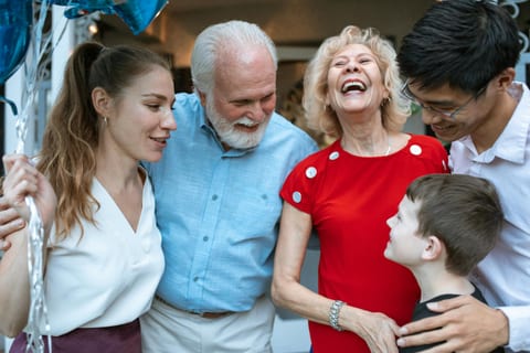 Generationenübergreifende Gruppe lacht gemeinsam bei einer Familienfeier